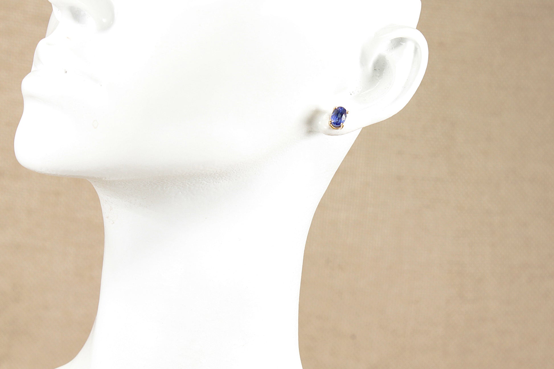 Gold blue topaz stud earring in the ear of a white mannequins head 