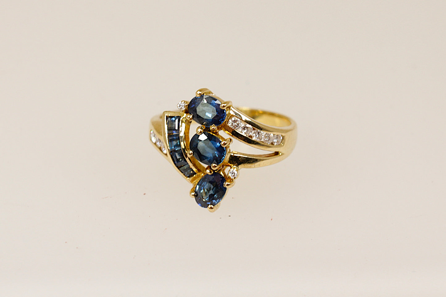 An 18ct gold cluster ring featuring multiple oval sapphires and round diamonds set asymmetrically, The ring is in excellent condition and inside the band it is stamped 750 for 18ct Gold.  UK Finger size N.