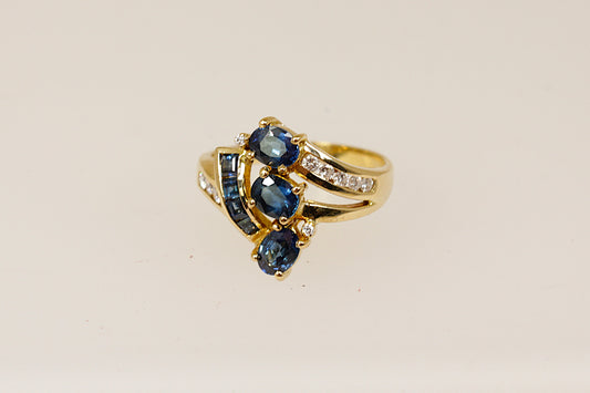 An 18ct gold cluster ring featuring multiple oval sapphires and round diamonds set asymmetrically, The ring is in excellent condition and inside the band it is stamped 750 for 18ct Gold.  UK Finger size N.