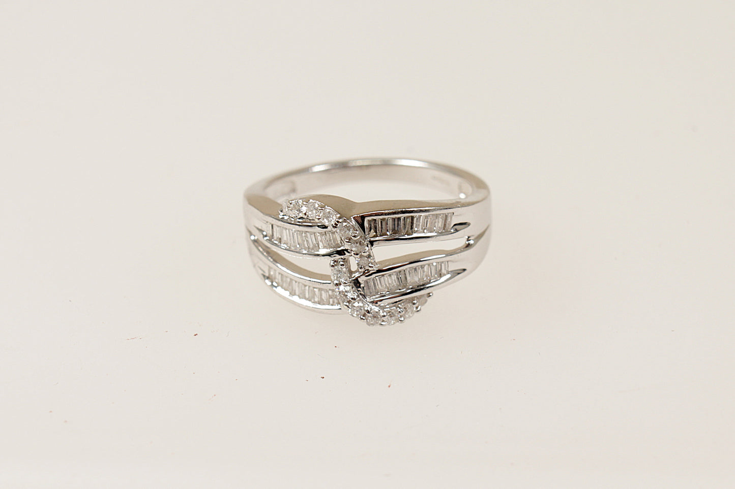 This stunning 9ct white gold cluster ring features 2 wave like shaped gold bands  that are encrusted with baguette Diamonds (32 baguette diamonds in total), There is a further 14 round diamonds that are set into a rope design , the ring has Birmingham hallmarks, UK finger size N. 