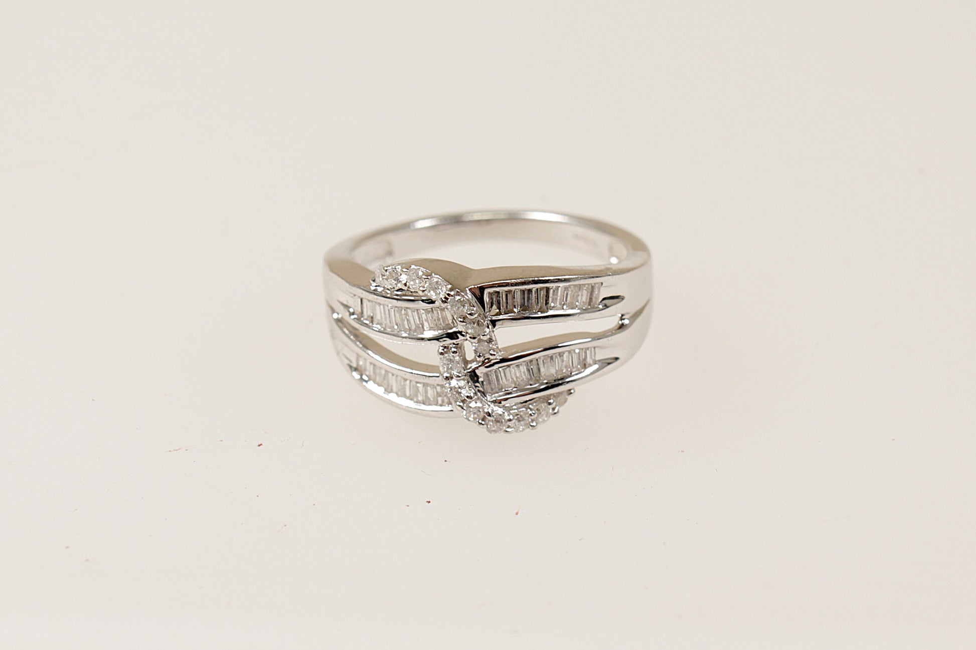 This stunning 9ct white gold cluster ring features 2 wave like shaped gold bands  that are encrusted with baguette Diamonds (32 baguette diamonds in total), There is a further 14 round diamonds that are set into a rope design , the ring has Birmingham hallmarks, UK finger size N. 