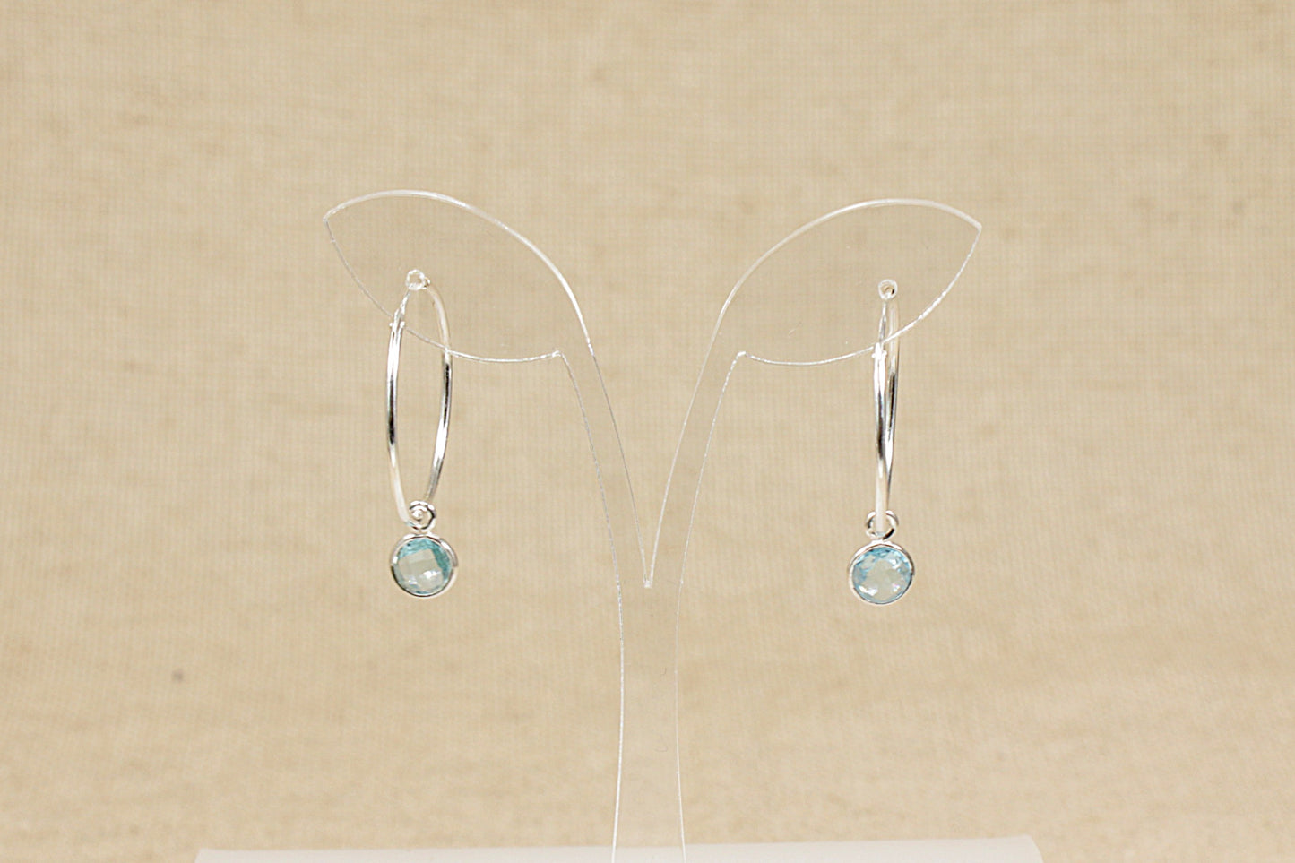 silver hoop earrings with blue topaz dropper front view