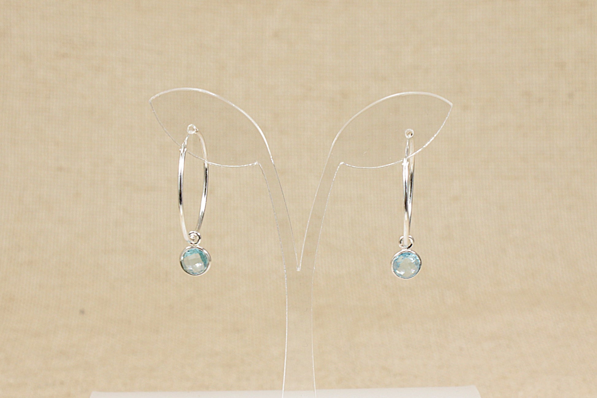silver hoop earrings with blue topaz dropper front view