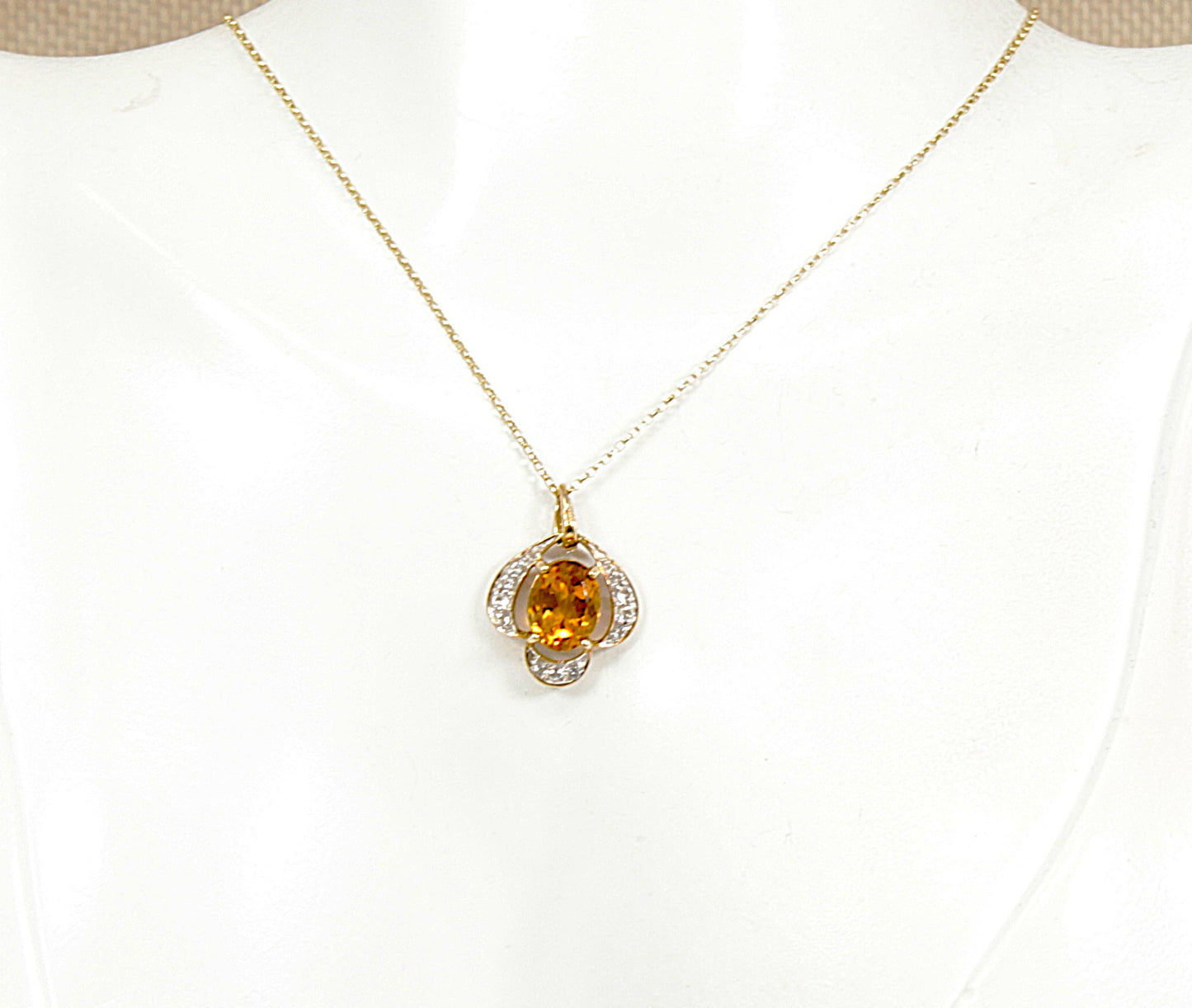 A gold chain necklace with a flower-shaped pendant featuring a central round citrine gemstone and small clear white citrine accent gemstones, displayed on a white jewelry bust.