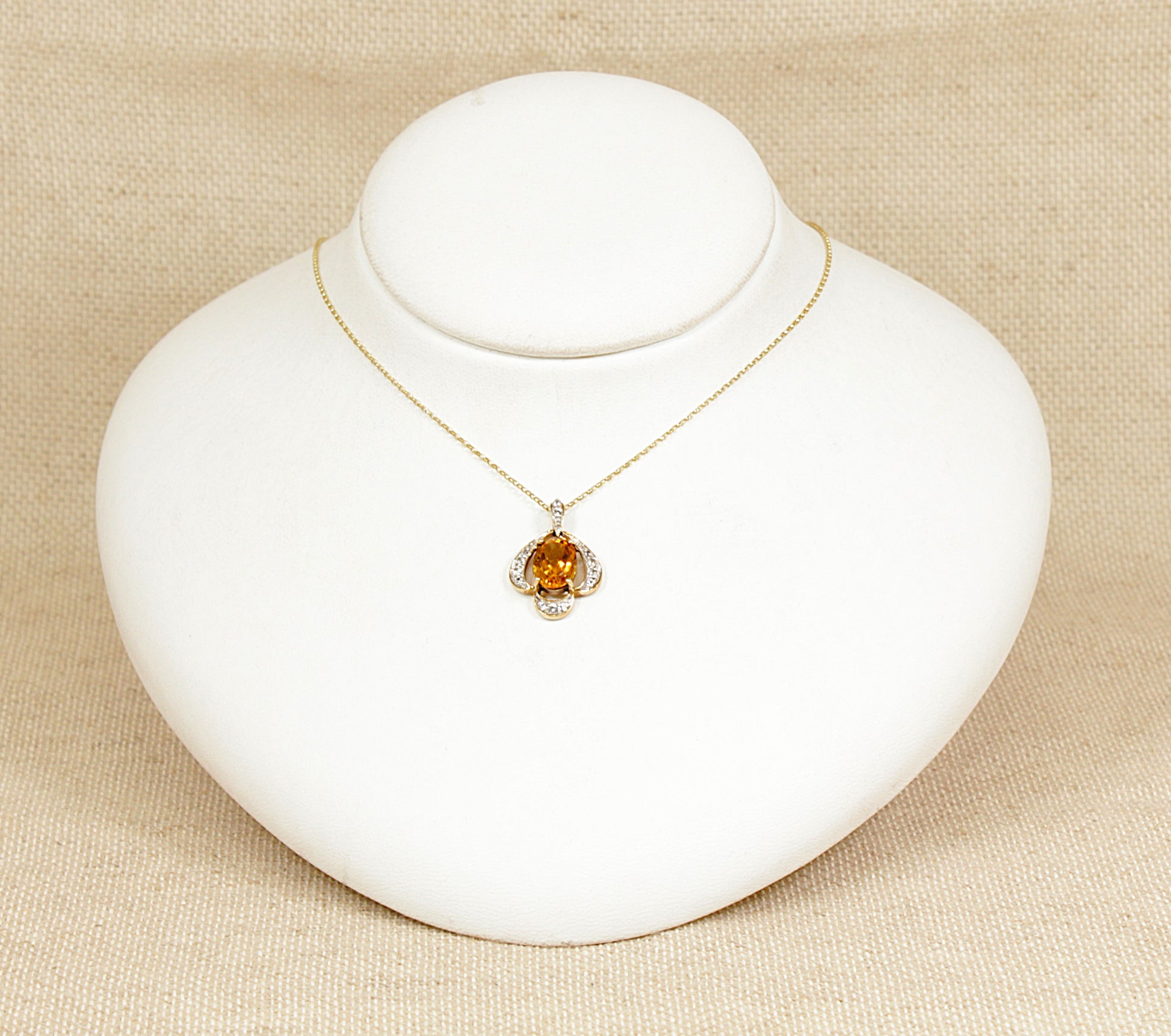 A stylish and elegant 9ct yellow Gold pendant featuring a vibrant oval-cut honey Citrine, securely set with four claws. Surrounding the Citrine is a beautifully crafted scalloped gold design, delicately accented with sparkling White Citrine stones to enhance the piece’s warmth and brilliance. Birmingham hallmarks.
