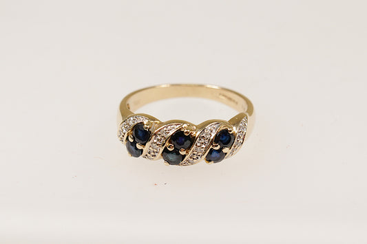 A 9ct gold ring featuring a slanted arrangement of round sapphires with diamond accents, claw set on the band.