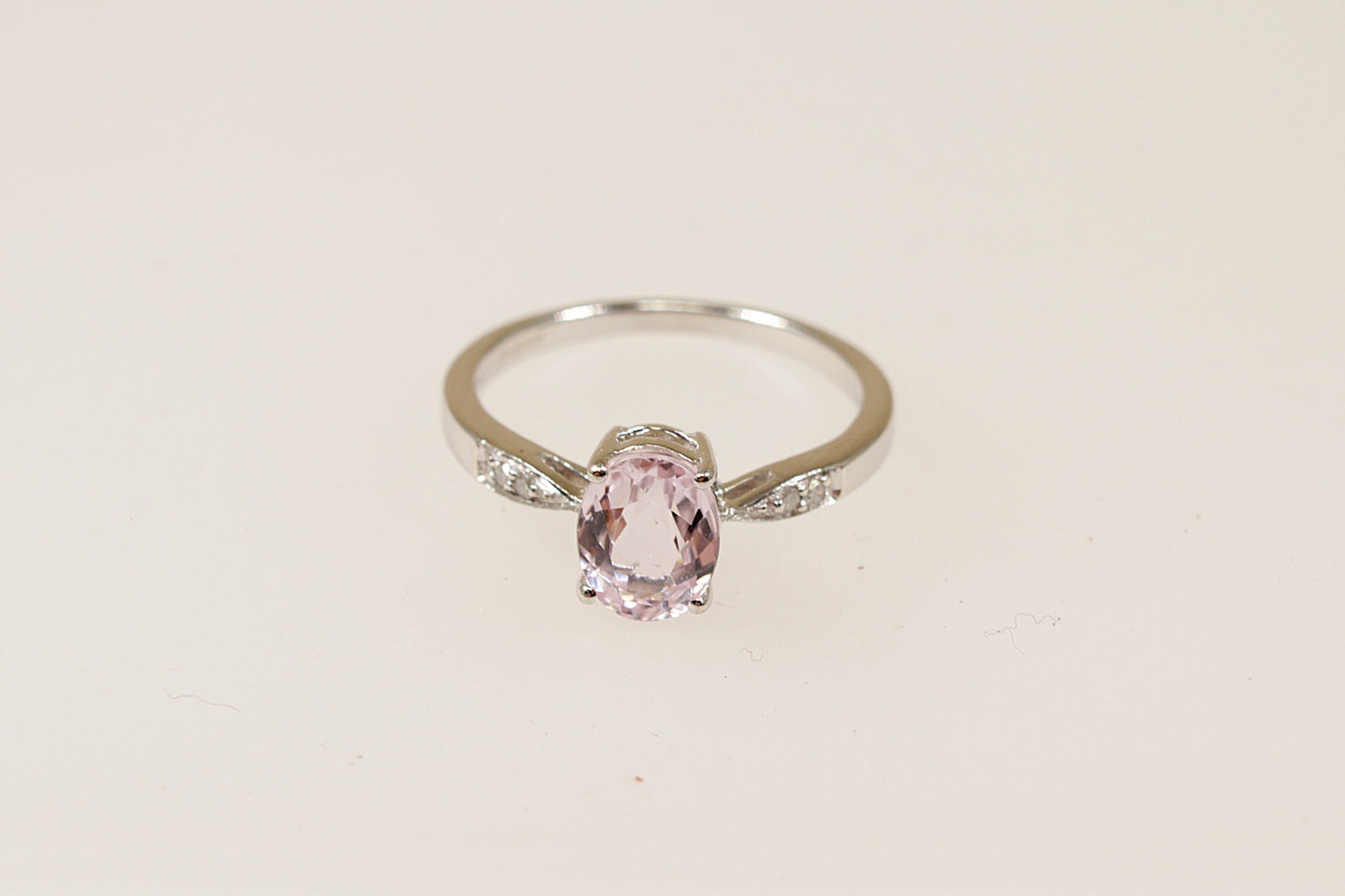 A 9ct white gold solitaire ring with an oval pink 'Rose de France' Amethyst centerpiece and diamond accents on the shoulders, displayed against a white background.