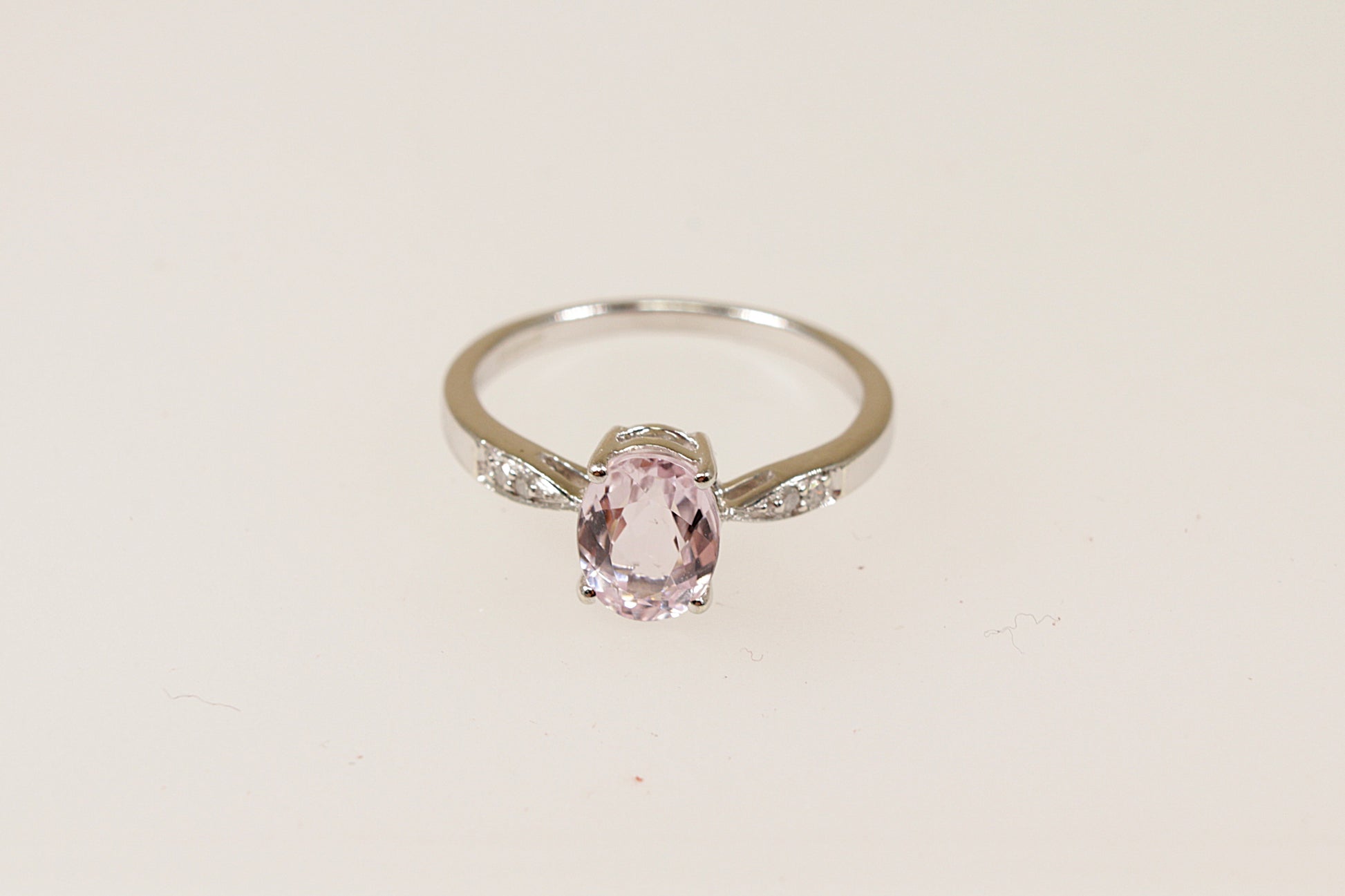 A 9ct white gold solitaire ring with an oval pink 'Rose de France' Amethyst centerpiece and diamond accents on the shoulders, displayed against a white background.