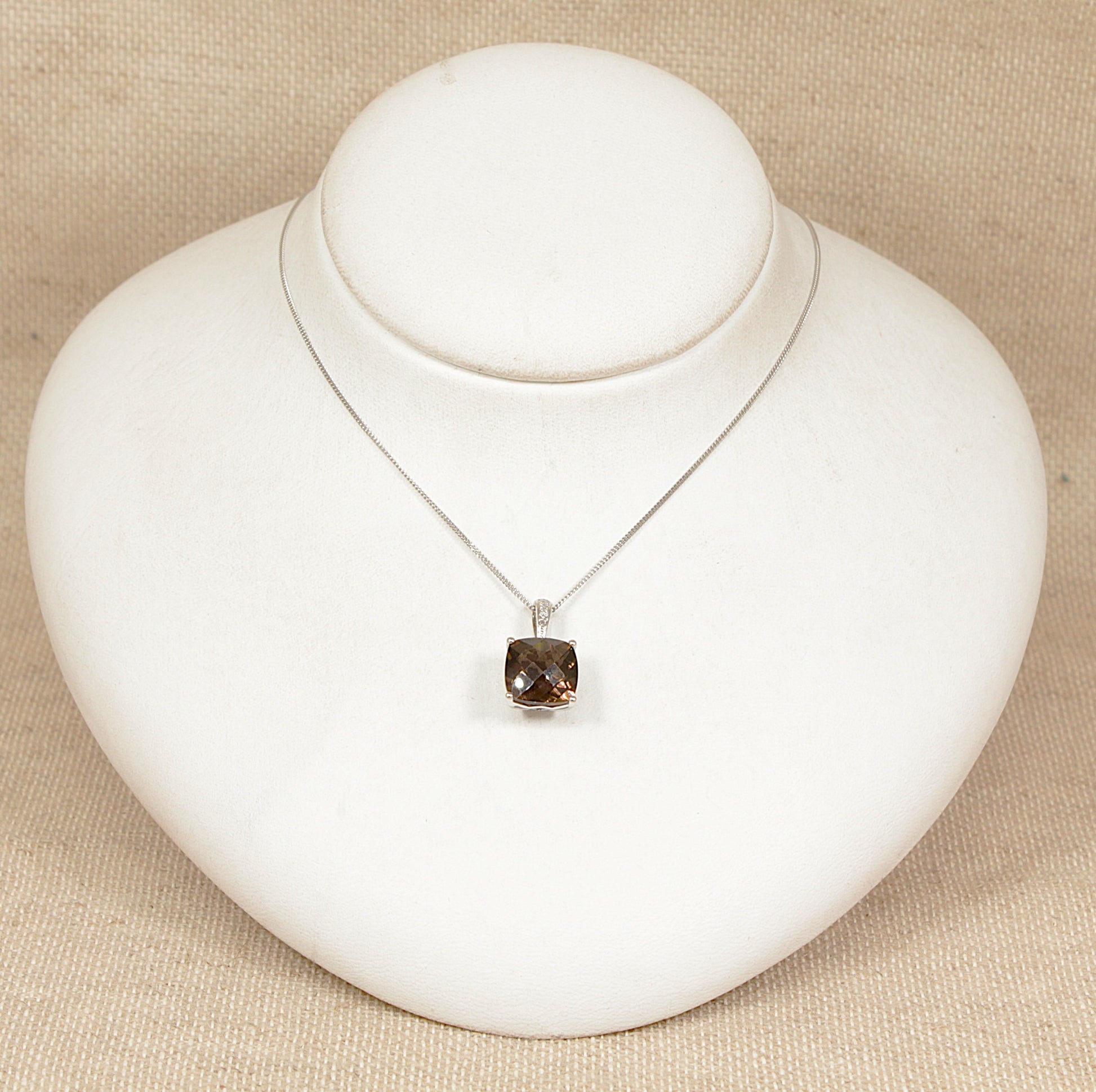 9ct white gold necklace with a smoky quartz pendant on a white stand against a beige background 