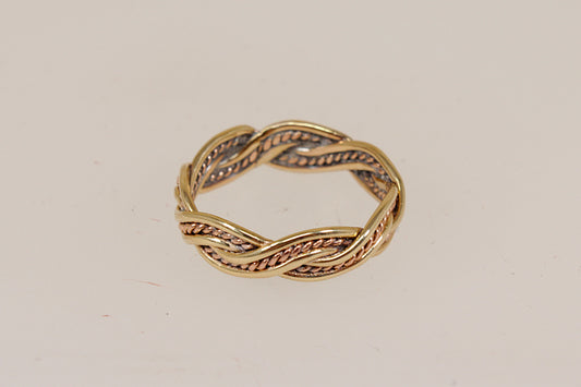 A twisted rope-style band ring in yellow gold with textured rose gold recessed detailing, photographed on a plain off-white background.