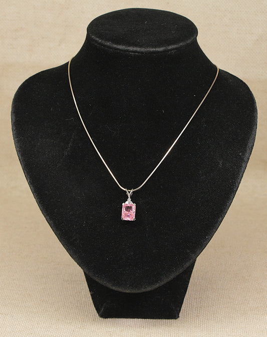 A sterling silver necklace with a rectangular pink gemstone pendant, displayed on a black necklace bust against a beige background.