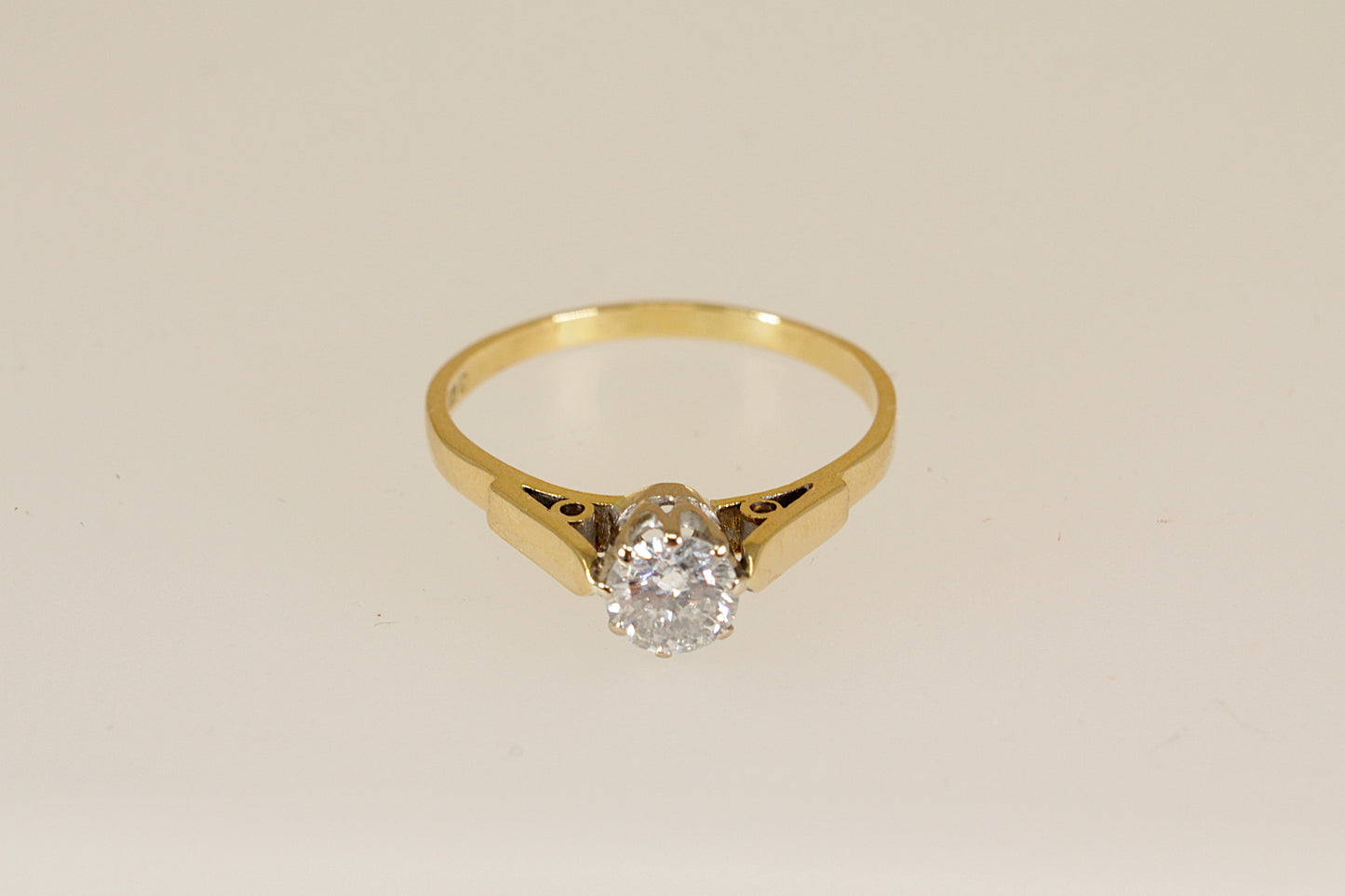 18ct Gold diamond solitaire ring on a beige background