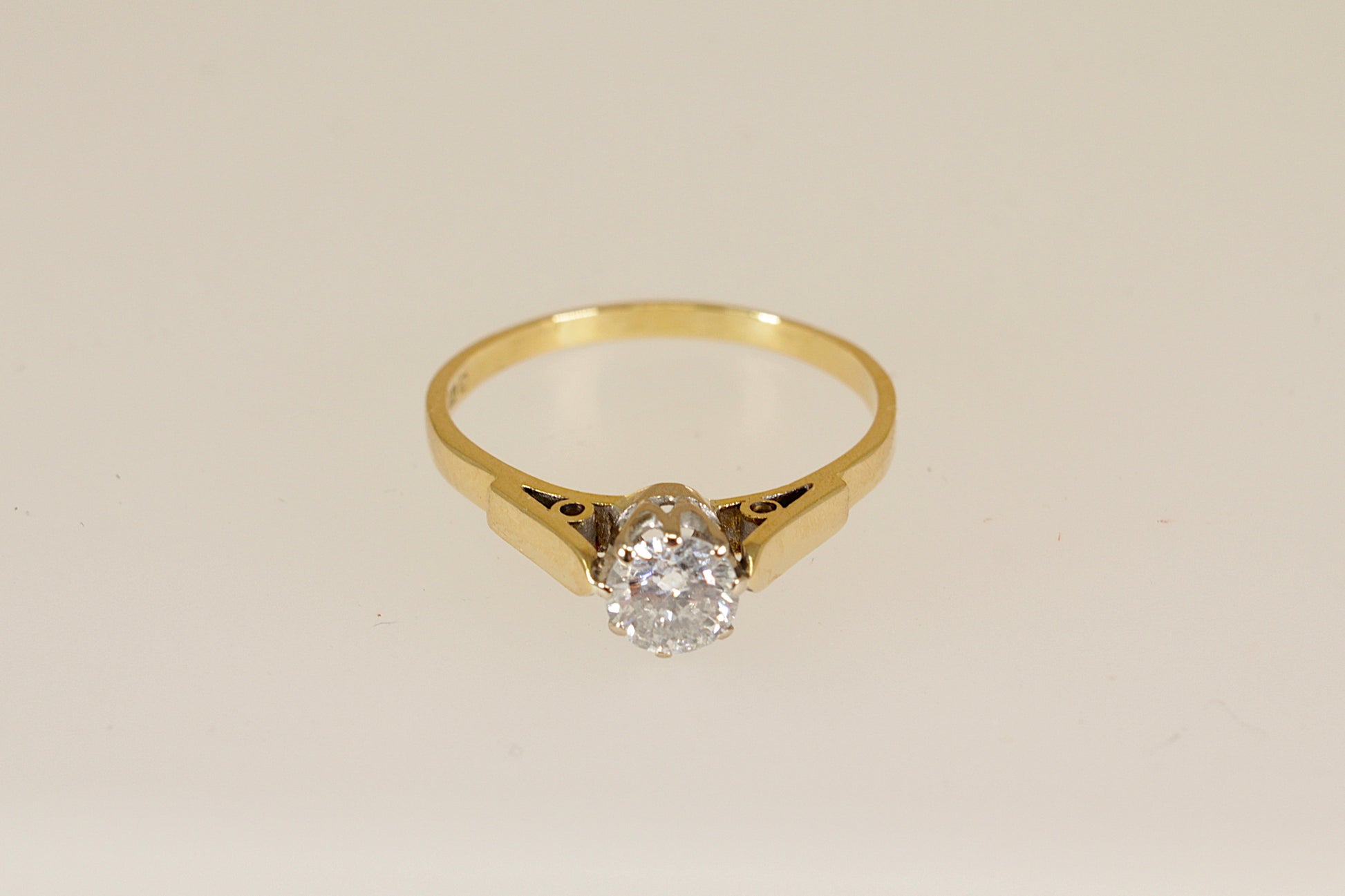 18ct Gold diamond solitaire ring on a beige background