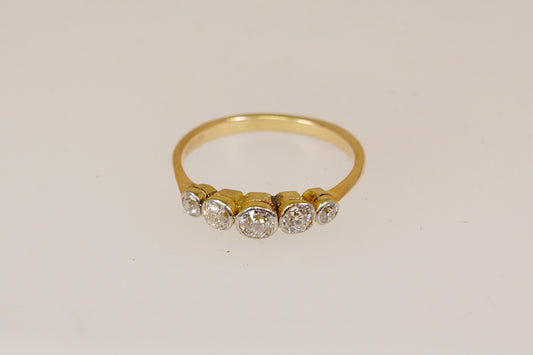 An 18ct yellow gold ring featuring five round-cut clear diamond gemstones set in a row on the band, photographed against a plain off-white background.