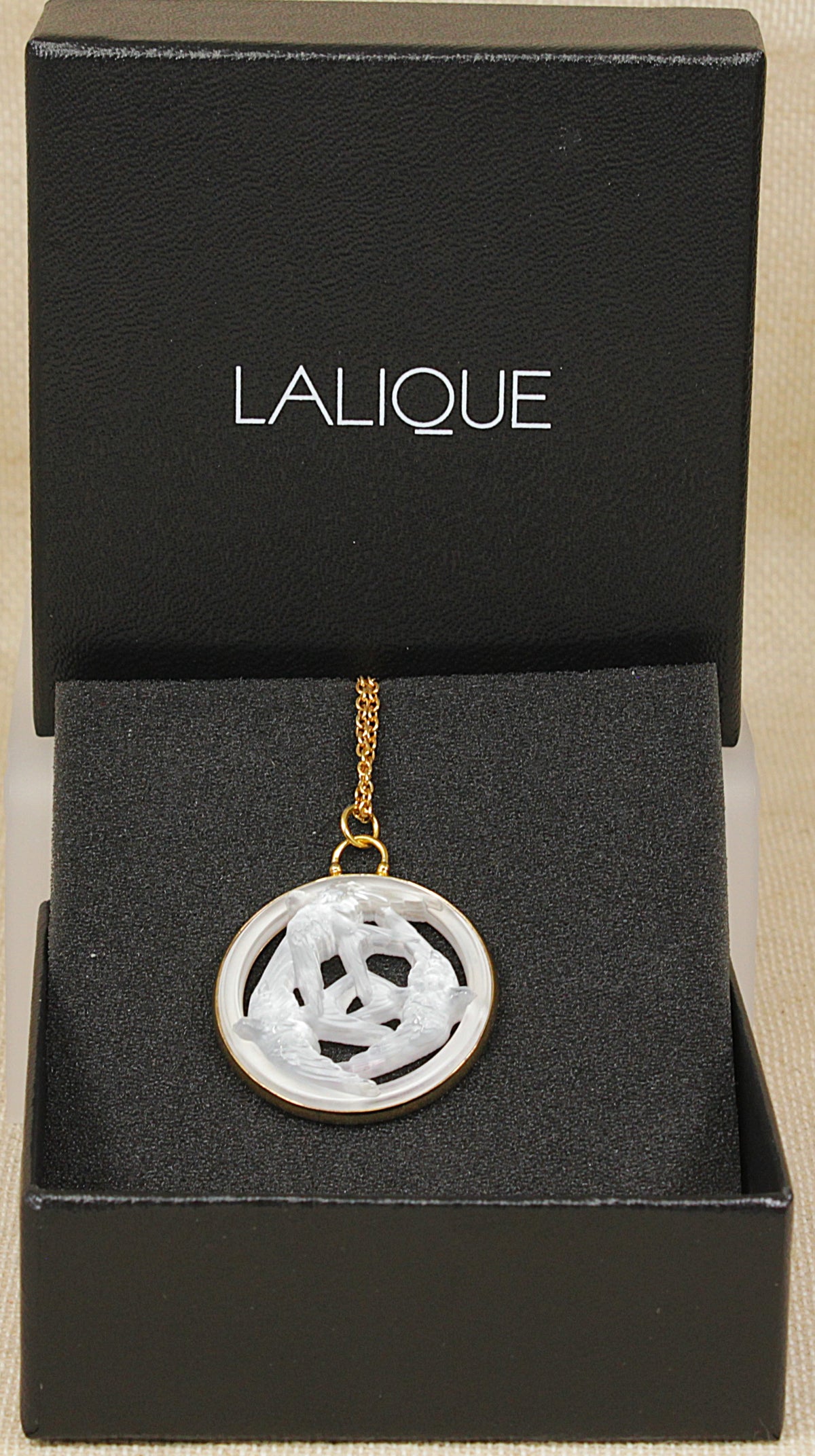 A Lalique brand pendant necklace with a white carved crystal three swallows  design and gold chain, presented inside an open black original lalique  box.