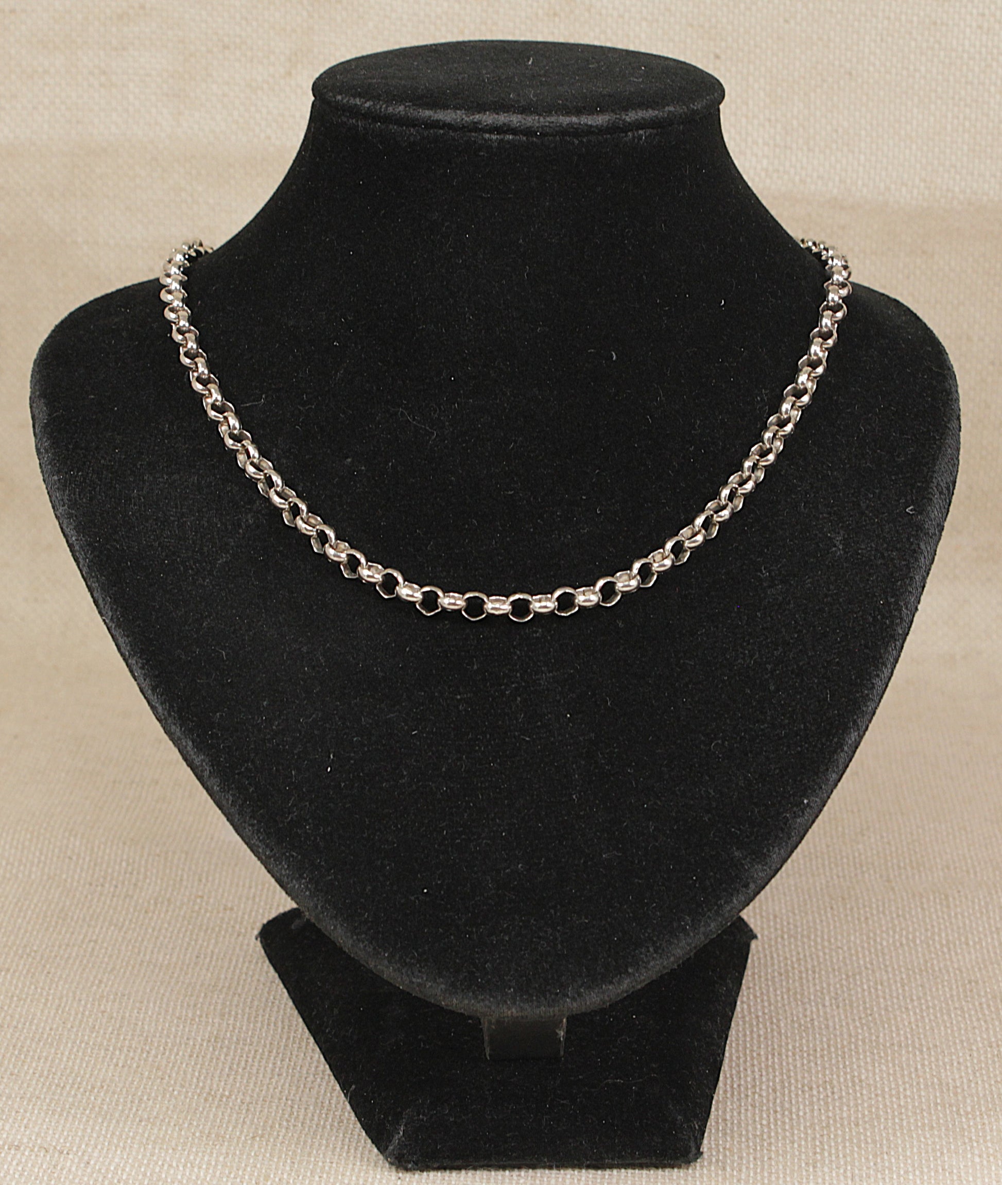 A vintage sterling silver neck chain necklace displayed on a black velvet jewelry bust against a light beige textured background.