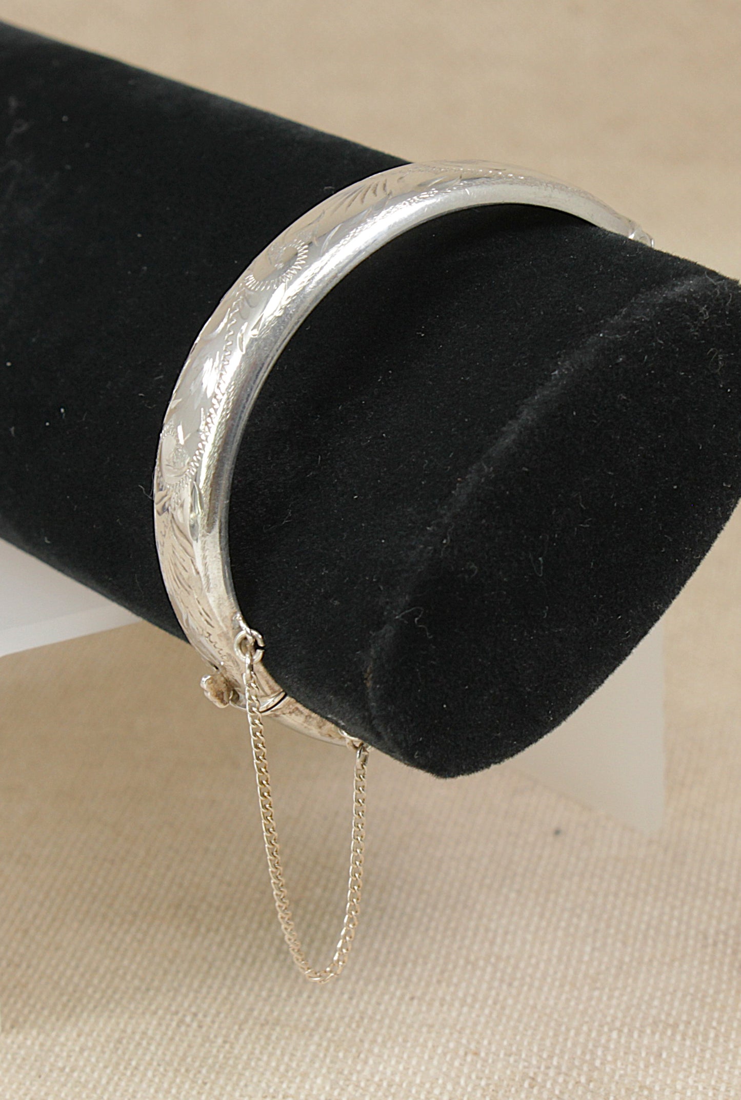 Vintage 1970's Silver bracelet with a safety chain on a black cylindrical stand.