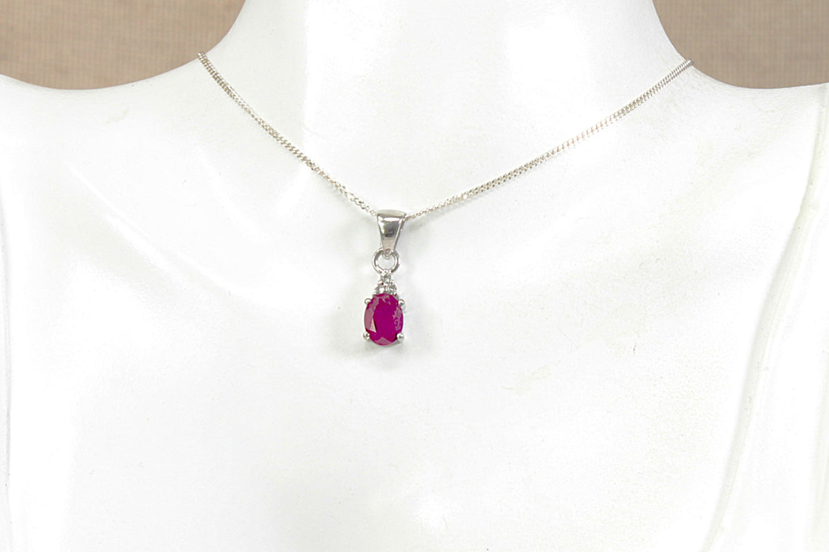A silver chain necklace with a teardrop-shaped redm gemstone pendant, displayed on a white mannequin bust.