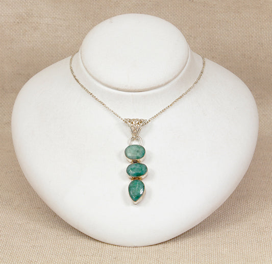 Necklace with green chrysoprase  pendant on a white stand against a beige background