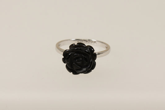 A silver ring with a black carved flower in the form of a rose, displayed against a white background.