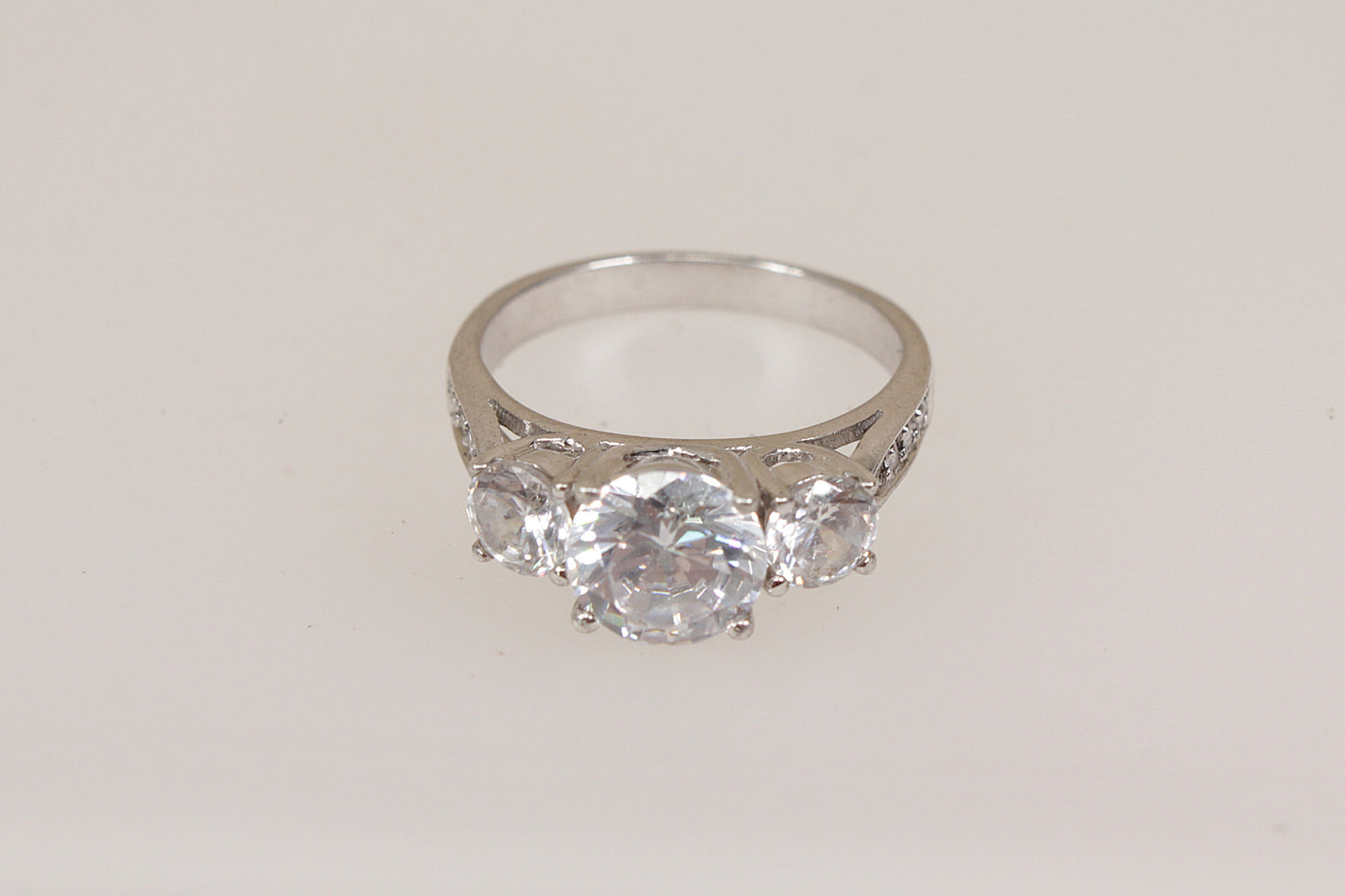 Silver ring with three clear cubic zirconia gemstones on a light gray background