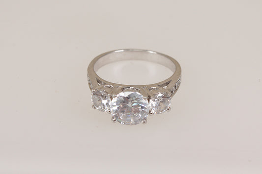 Silver ring with three clear cubic zirconia gemstones on a light gray background