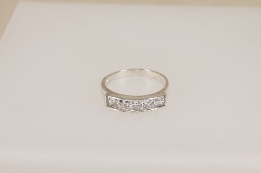 Silver ring with embedded diamond simulant crystal gemstones on a light beige background