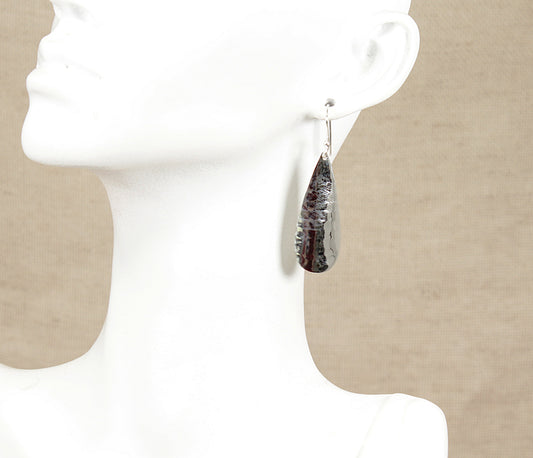 Teardrop-shaped silver earrings on a mannequin with a neutral background