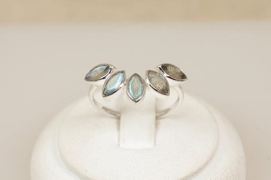 Silver ring with a half halo of labradorite gemstones on a white stand