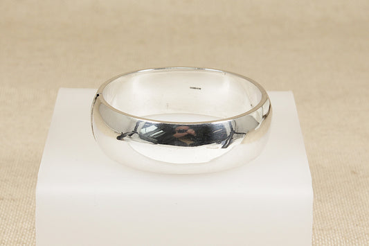 Silver hinged cuff bangle bracelet on a white stand with a beige background