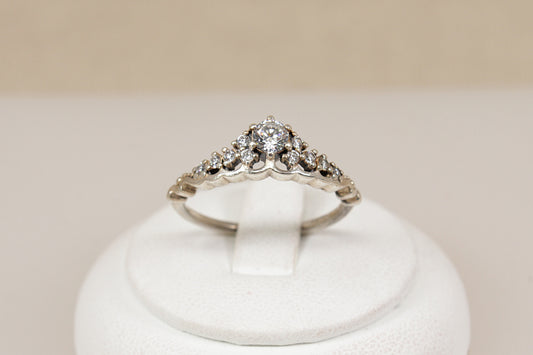A silver pandora tiara crystal ring with a pointed, crown-like top, displayed on a white jewelry stand against a soft beige background.