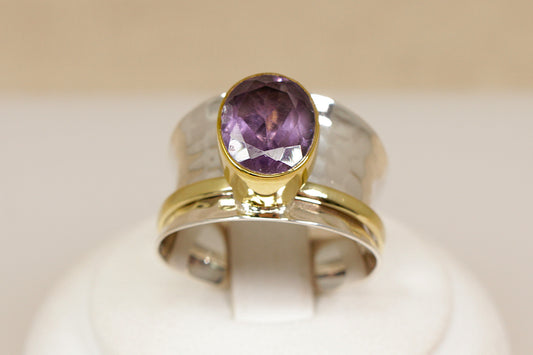Ring with a purple amethyst gemstone and gold band on a beige background
