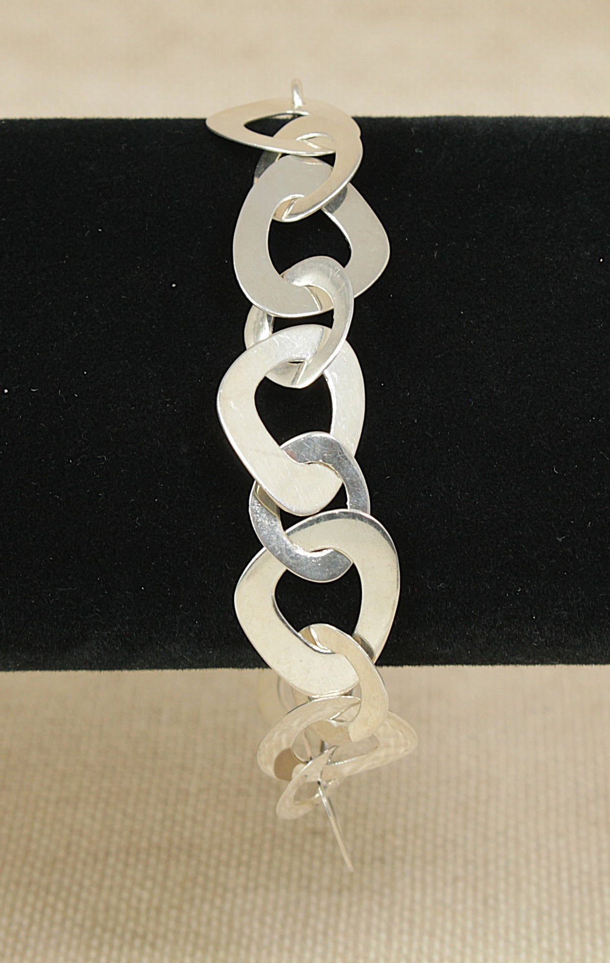 Silver designer chain bracelet on a black and beige background