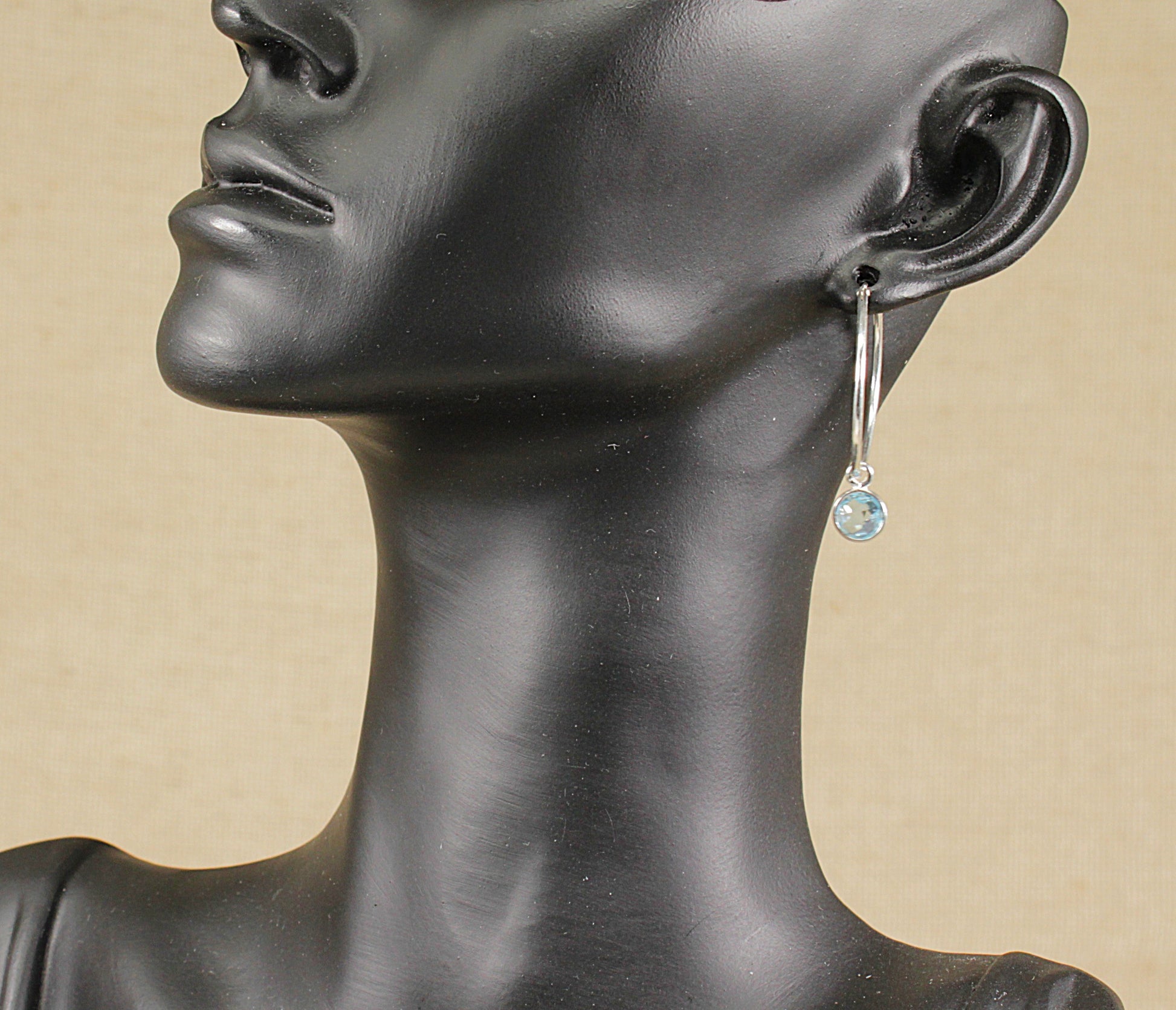 This pretty pair of silver fine hoop earrings features a round Blue faceted Topaz dropper. The hoops have a classic smooth finish.&nbsp; Suspended from the hoop is a round, blue Topaz, that is bezel set and dangles gracefully, and catches the light beautifully. Hoop: 25mm diameter.