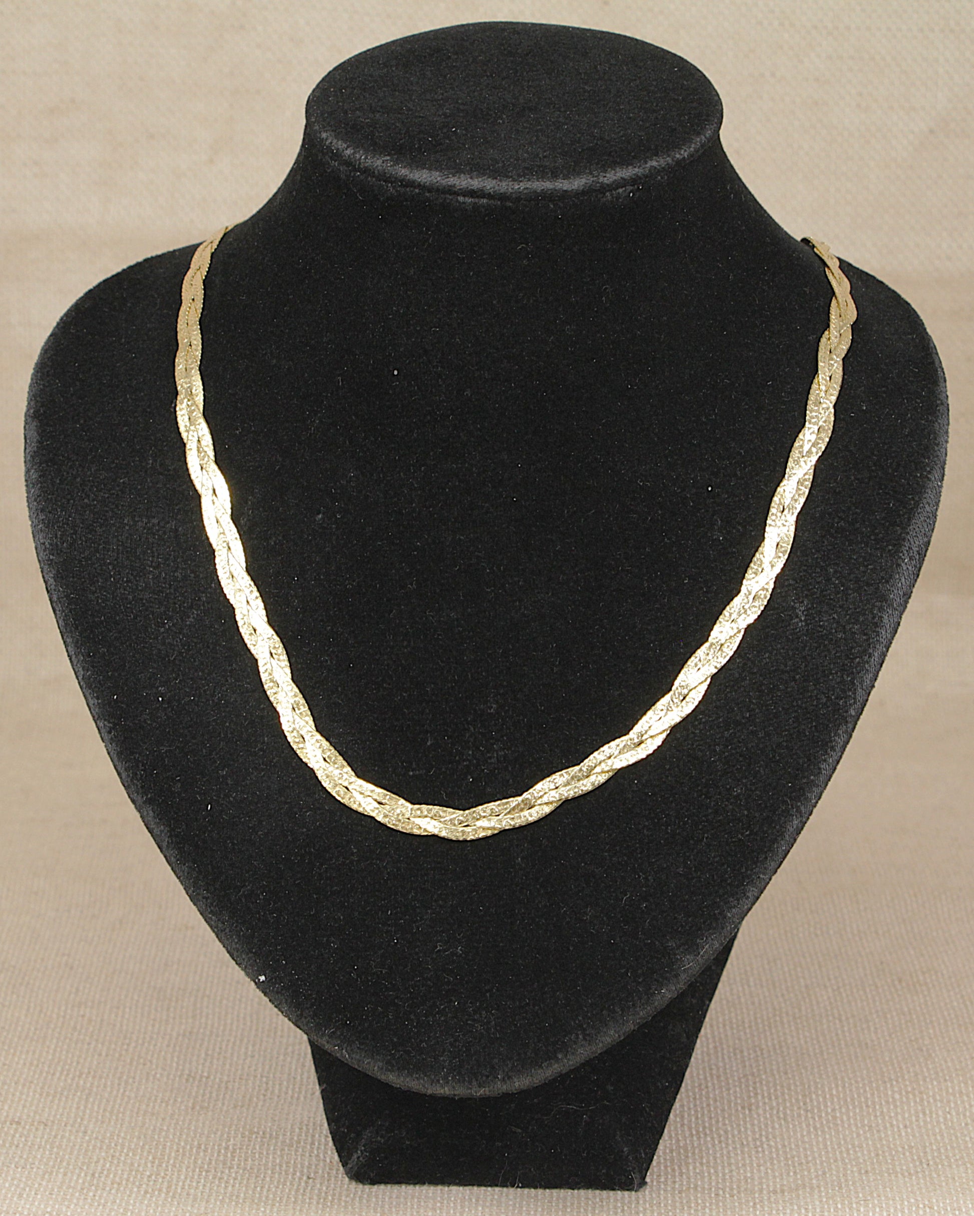 A gold-toned Italian designed sterling silver twisted chain necklace displayed on a black velvet jewelry bust against a light beige background.