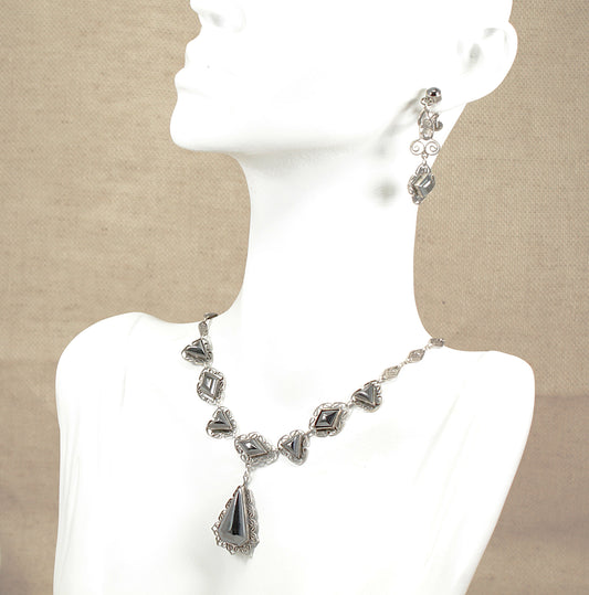 Vintage silver hematite necklace and earrings on a mannequin with a beige background